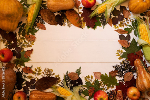 Frame composition with autumn leaves, red apples, corn, walnuts and pumpkins on a old wooden background. Fall texture. Nature september and october background. Copy space, top view. Toned photo.