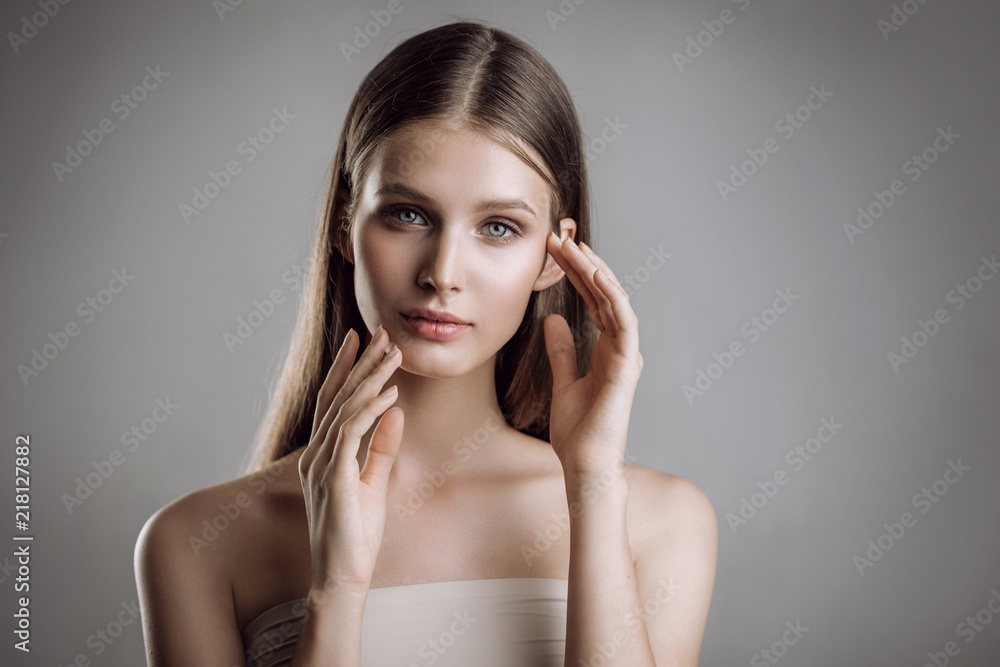 Portrait of a beautiful young girl with nude make-up in studio on a gray background Portrait of a beautiful young girl with nude make-up in studio on a gray background