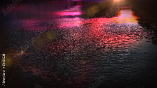 Light and shadows of the night city. Wet asphalt with neon. Soft image of the focus of the street after the rain with reflections on the wet asphalt. Blurred background.
