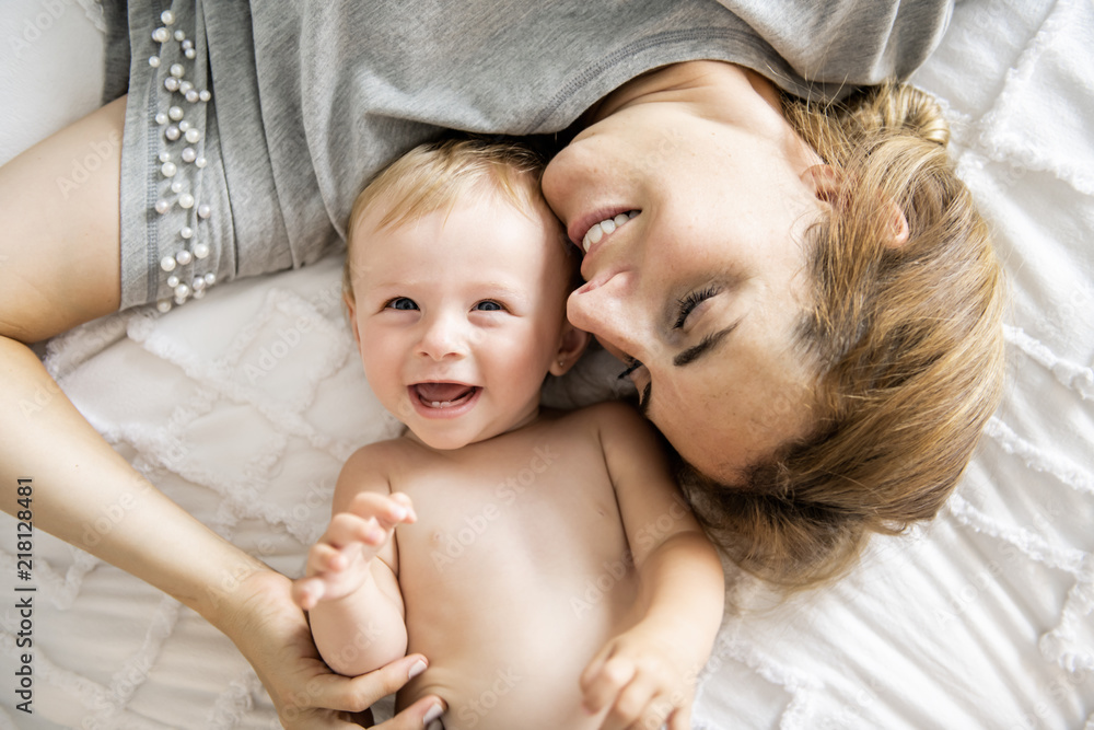 Mother and baby girl on a white bed Mother and baby girl on a white bed