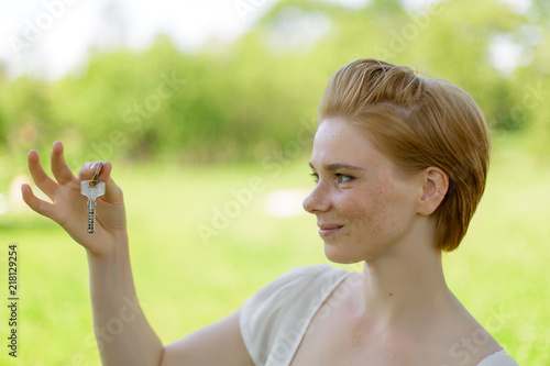 Real estate. Happy broker. Attractive young woman holding keys while standing outdoor against park