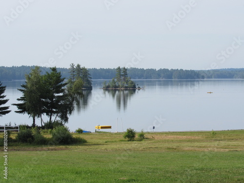 View across a field of Damariscotta Lake in Maine with a person kayaking in the distance 
