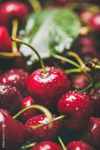 Fresh sweet cherry texture, wallpaper and background. Wet sweet cherries with leaves, selective focus, close-up, vertical composition. Summer food or local market produce concept