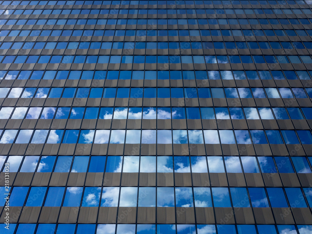 Office building windows with reflecting blue sky and clouds