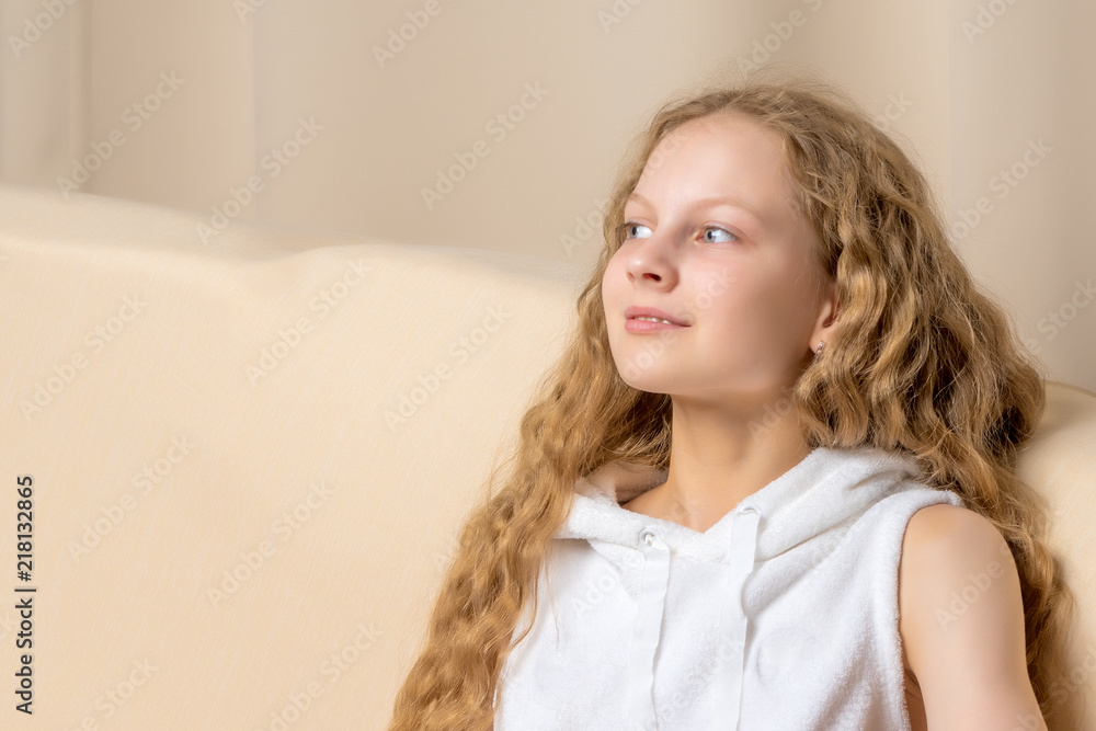 Naklejka premium Little girl is sitting on the couch