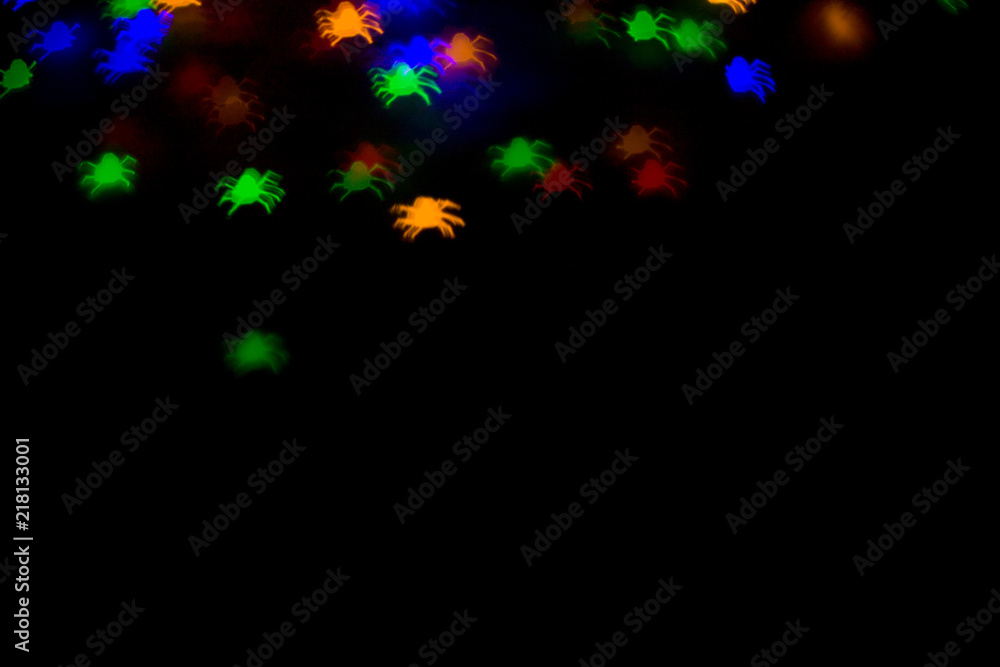 holidays, decoration and party concept - defocused bokeh multicolor lights in shape of spiders for halloween background. copy space