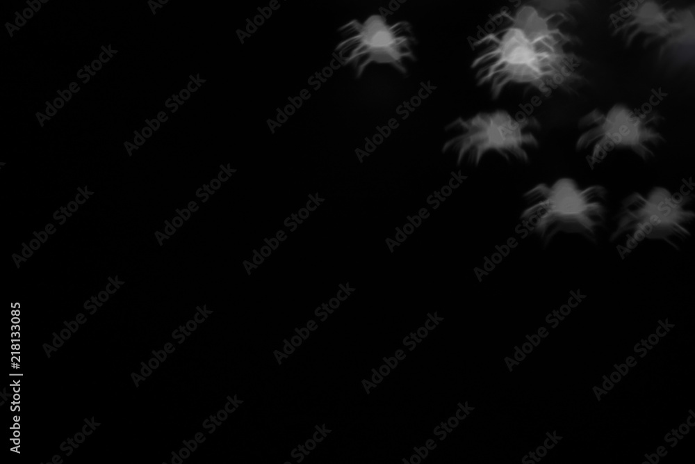 holidays, decoration and party concept - defocused white spiders silhouette ghosts on black for halloween background