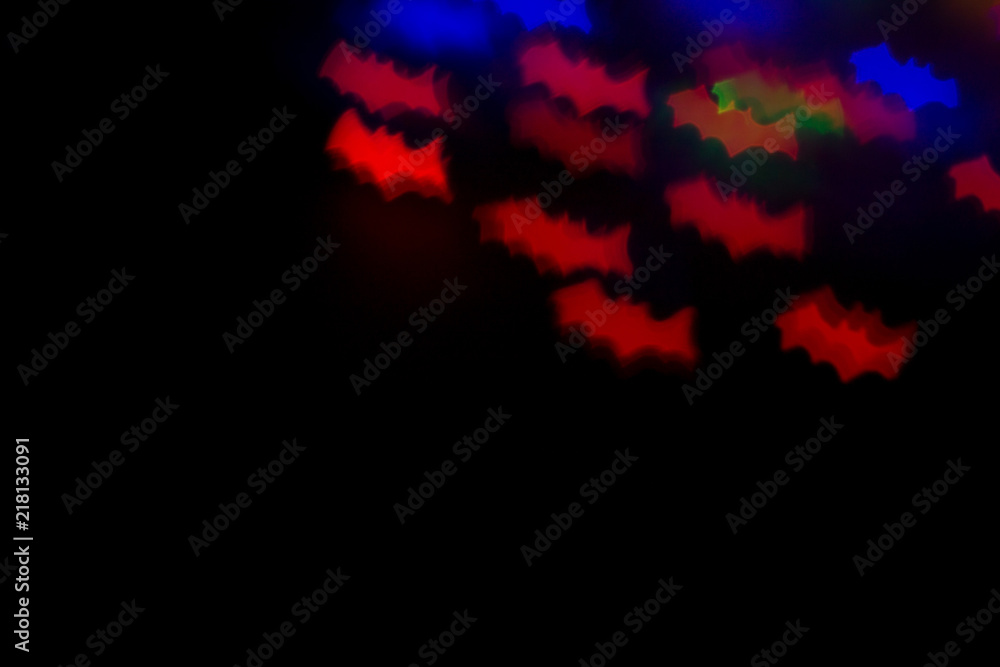 holidays, decoration and party concept - defocused bokeh multicolor lights in shape of bats for halloween background. copy space