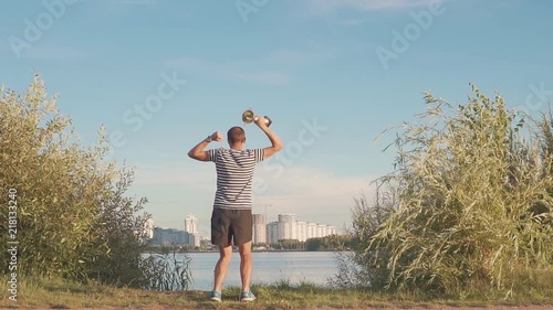 man with a cup in his hands rejoices in sports victory. Dances and jumps on evening city. Slow motion