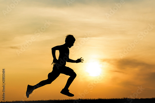 Silhouette of boy running at sunset.