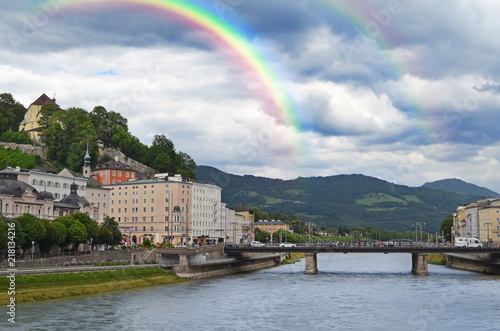 SALZBURG, AUSTRIA - JUNE 22, 2018: Picturesque view of city street on riverside and rainbow in sky