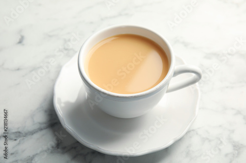 Cup with black tea and milk on marble table