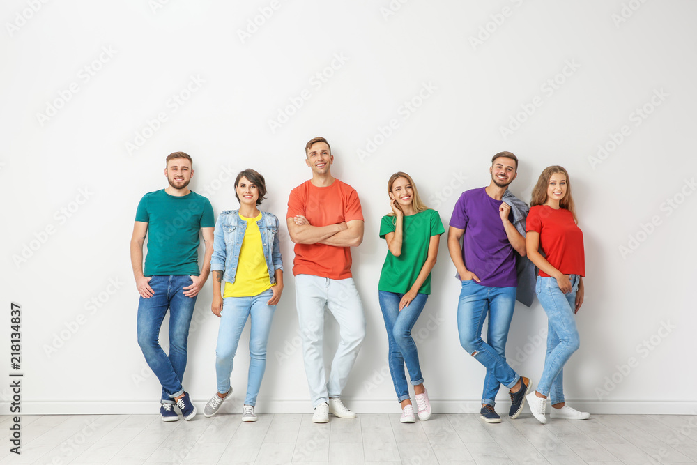 Fototapeta premium Group of young people in jeans and colorful t-shirts near light wall