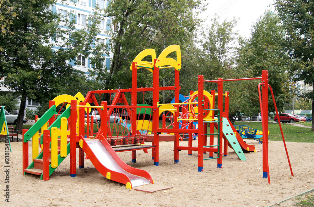 Children's playground with red structures and a small hill.