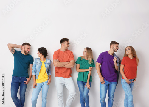 Group of young people in jeans and colorful t-shirts on light background