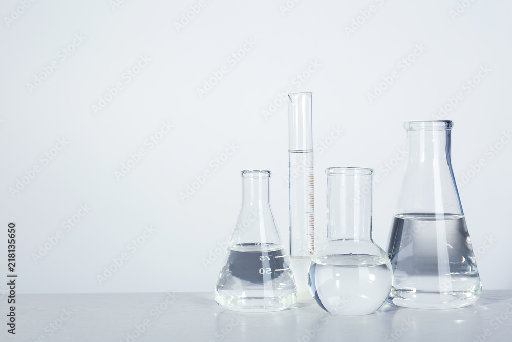 Laboratory glassware with liquid on table against light background. Chemical analysis Laboratory glassware with liquid on table against light background. Chemical analysis