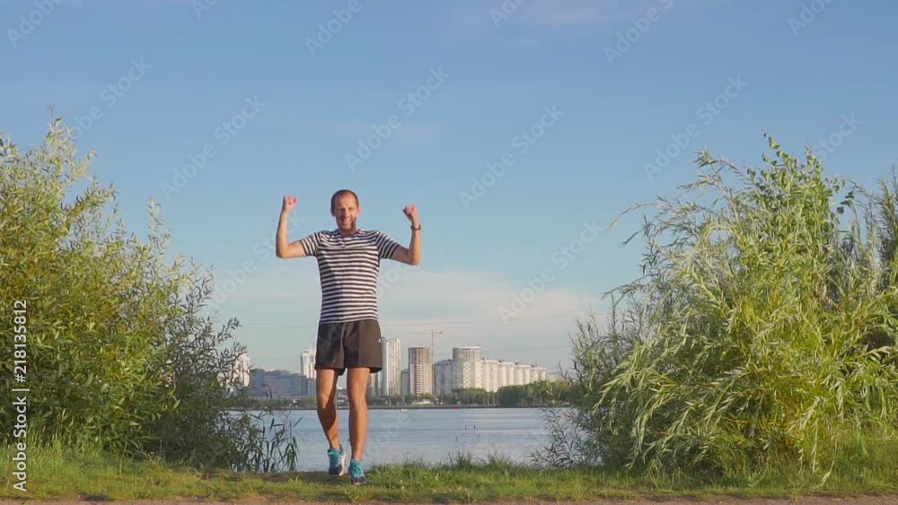 man with a cup in his hands rejoices in sports victory. Dances and jumps on evening city. Slow motion man with a cup in his hands rejoices in sports victory. Dances and jumps on evening city. Slow motion