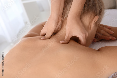 Relaxed woman receiving neck massage in wellness center