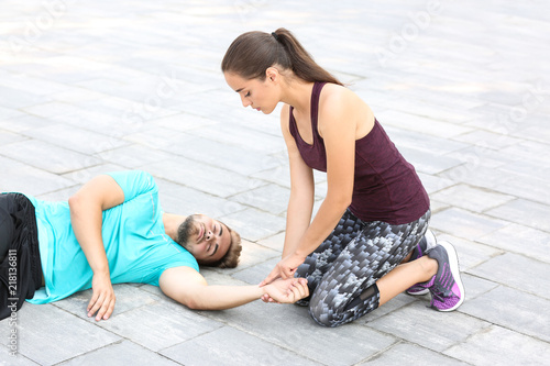 Woman checking pulse of unconscious man outdoors