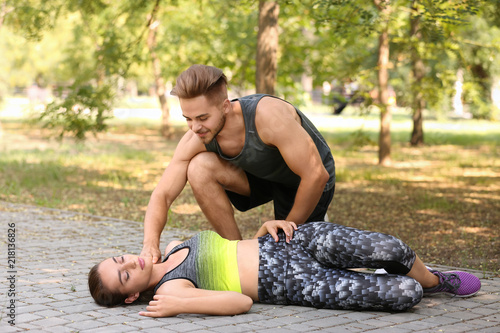 Man checking pulse of unconscious woman outdoors