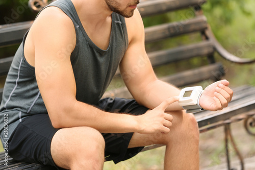 Young man checking pulse outdoors on sunny day