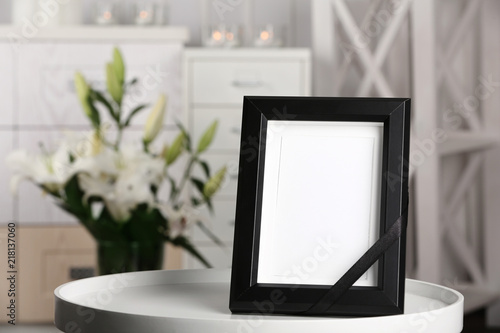 Fototapeta Naklejka Na Ścianę i Meble -  Funeral photo frame with black ribbon on table, indoors