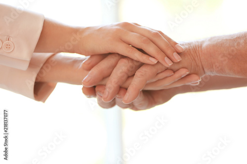 Fototapeta Naklejka Na Ścianę i Meble -  Young woman holding elderly man hands on blurred background, closeup. Help service