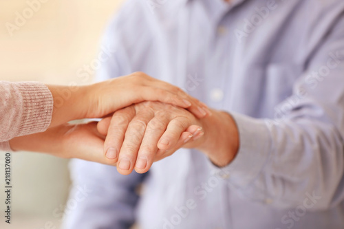 Young woman holding elderly man hand, closeup. Help service