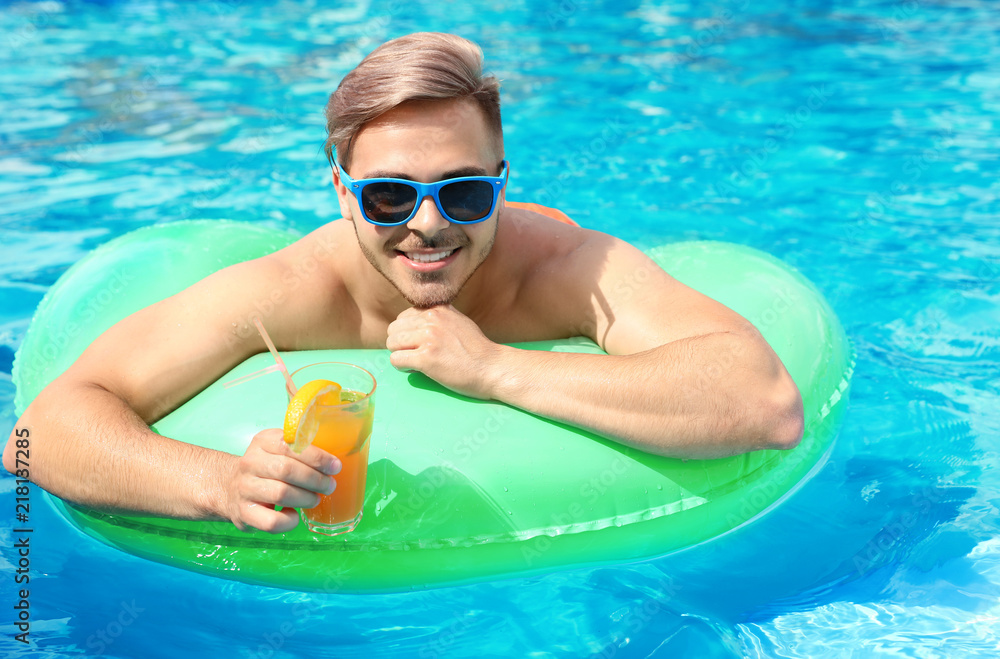 Fototapeta premium Young man with cocktail in pool on sunny day