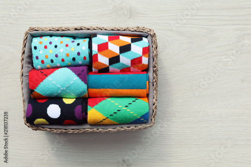 Box with colorful socks on wooden background, top view