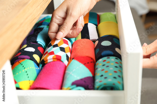 Woman opening drawer with different colorful socks indoors, closeup photo