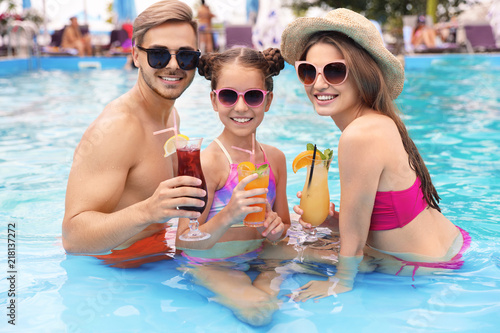 Happy family with cocktails in pool on sunny day