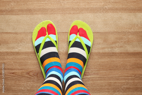 Woman wearing bright socks with flip-flops standing on floor, top view