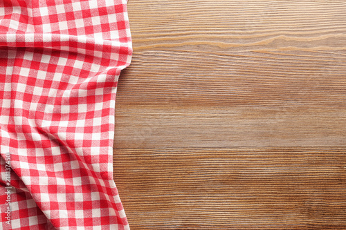 Checkered picnic tablecloth on wooden background, top view