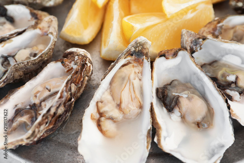 Fresh oysters with cut juicy lemon on plate  closeup