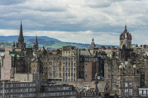 Edinburgh, Scotland, UK - June 13, 2012: Looking from Calton Hill upon dark brown builidngs of old town under heavy cloudscape. Towers such as St. Giles Cathedral and others. Green hills on horizon.