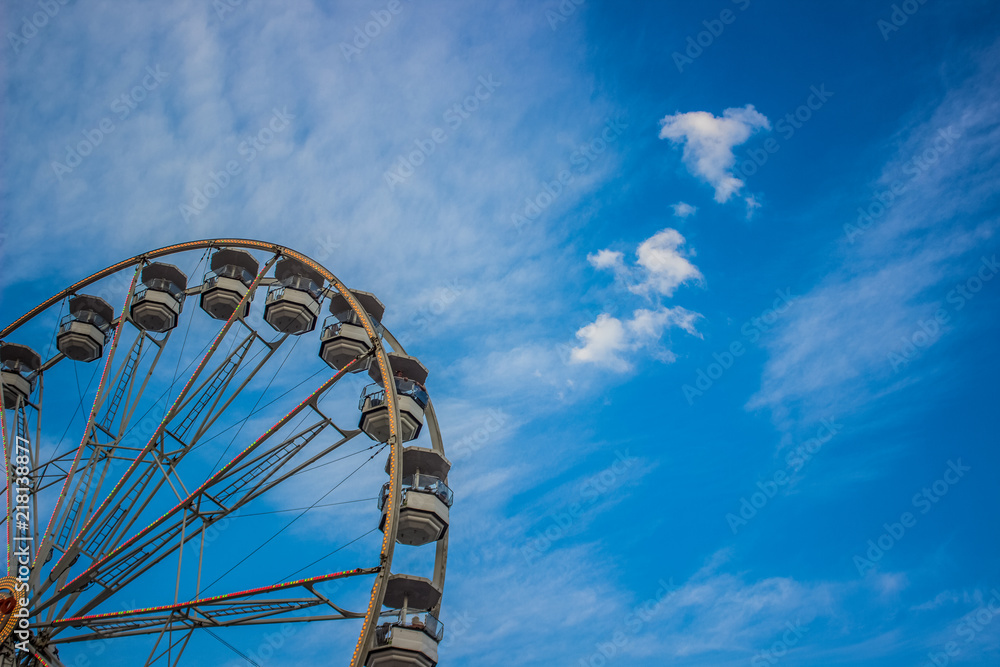 carnival entertainment concept of colorful shoot of ferris wheel metal construction element on blue sky background with empty space for copy or text carnival entertainment concept of colorful shoot of ferris wheel metal construction element on blue sky background with empty space for copy or text