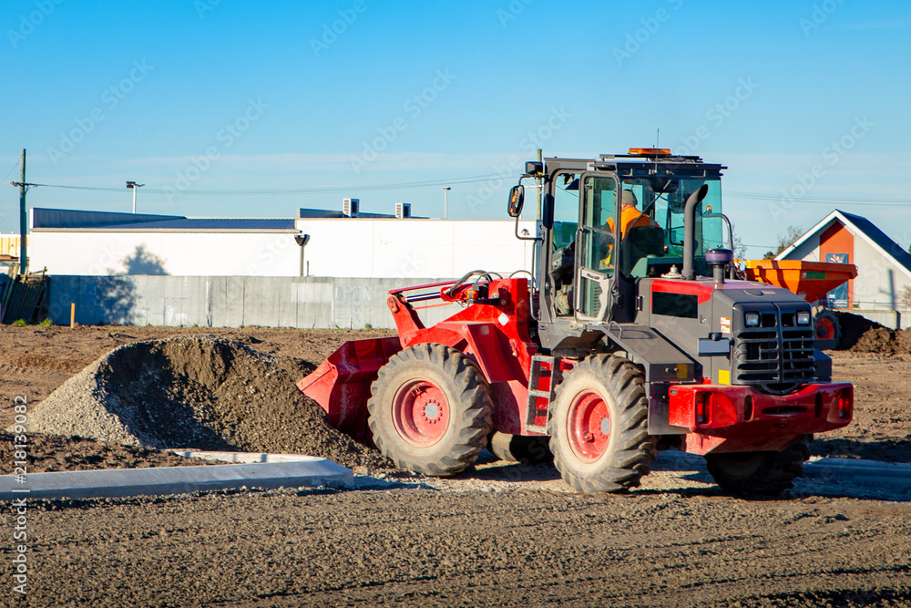 Fototapeta premium A red loader used at a building site to shift piles of gravel and dirt 