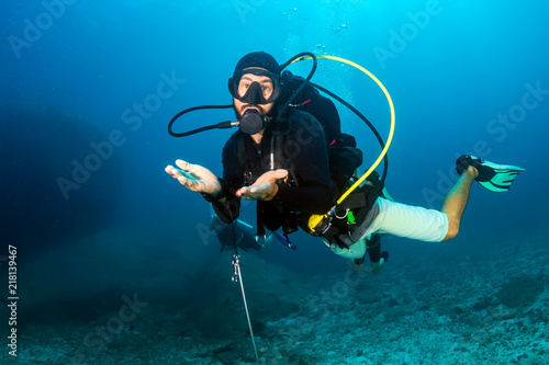A SCUBA diver exploring a dark tropical coral reef © whitcomberd