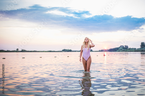 Beautiful girl posing in water at sunset