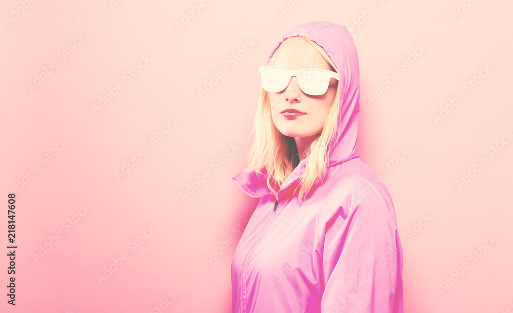 Fashionable woman in pink raincoat and sunglasses on a pink background Fashionable woman in pink raincoat and sunglasses on a pink background