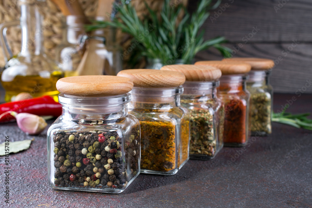 Glass jars with dry spices for cooking on dark table Glass jars with dry spices for cooking on dark table