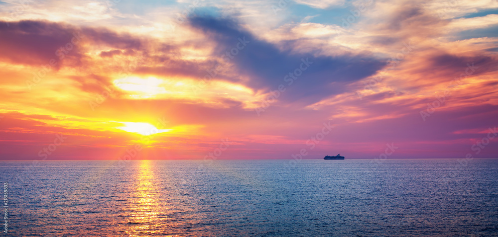 dramatic sunset at the sea with ferry on the background. Beautiful sky with clouds and ocean