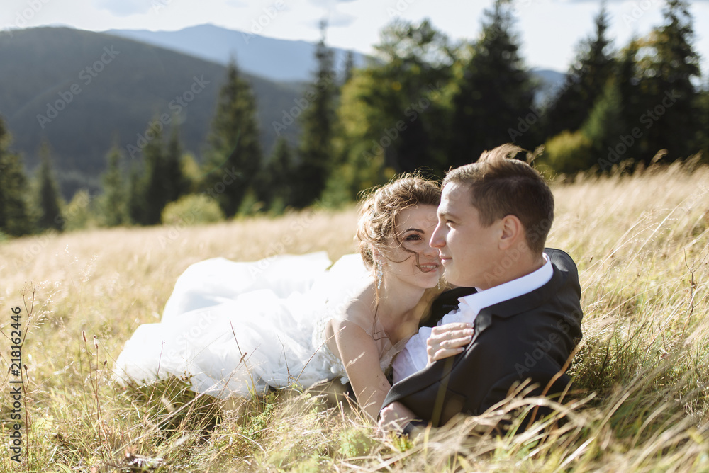 Happy wedding couple lying on green grass at the summer time Happy wedding couple lying on green grass at the summer time