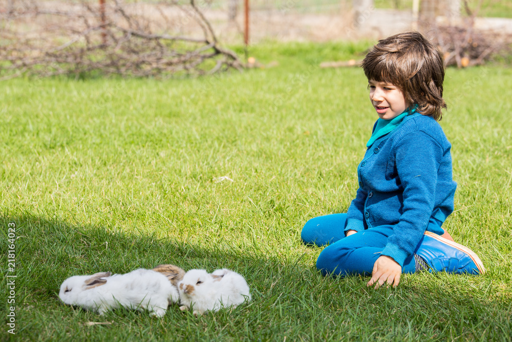 Boy sitting on grass with little rabbits Boy sitting on grass with little rabbits