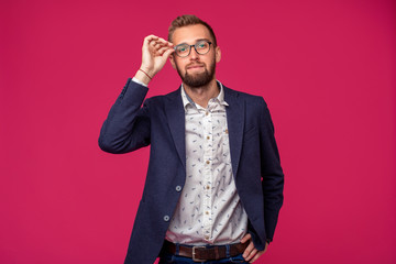 Portrait view of an attractive happy businessman with glasses on a pink background