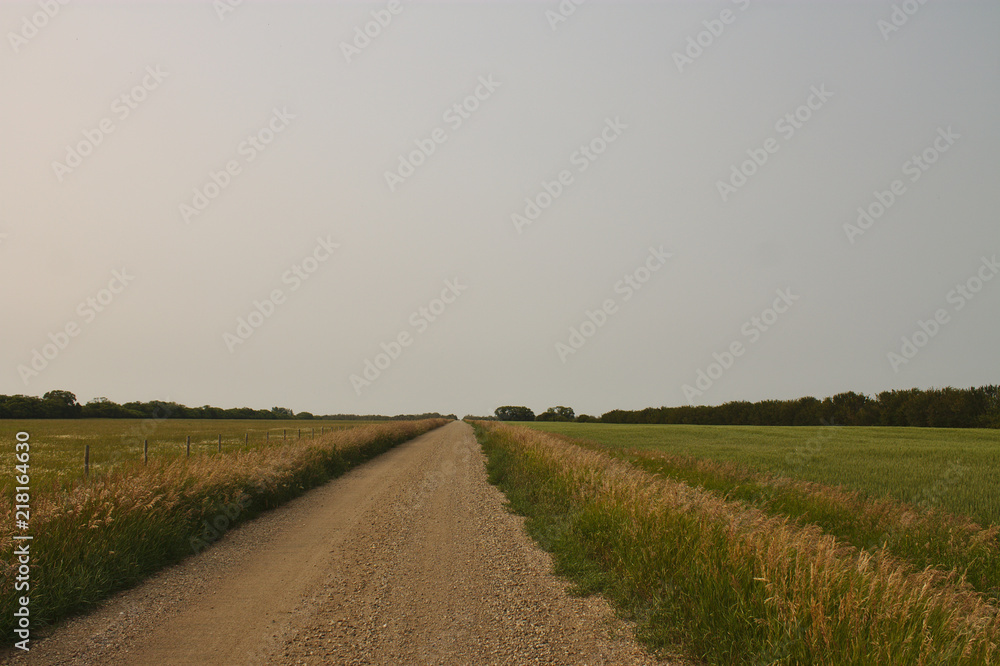 Back-road in Canadian Prairies with lightly hazy sky from local wildfires.
