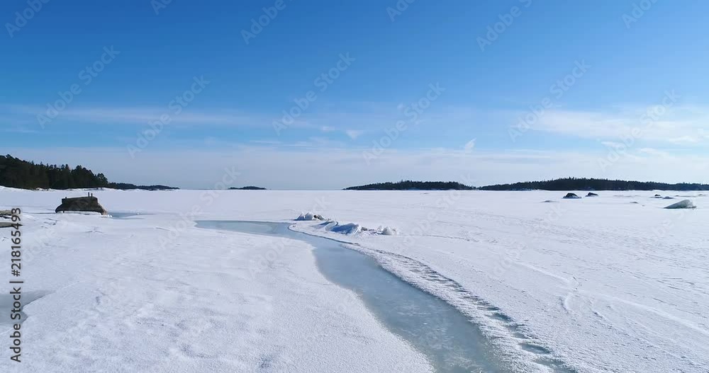 Snowy ice covered sea. Drone flying forward low following melted path. Rocks revealing under cracked ice. Clear blue fresh sunny winter day. Helsinki Finland. Snowy ice covered sea. Drone flying forward low following melted path. Rocks revealing under cracked ice. Clear blue fresh sunny winter day. Helsinki Finland.