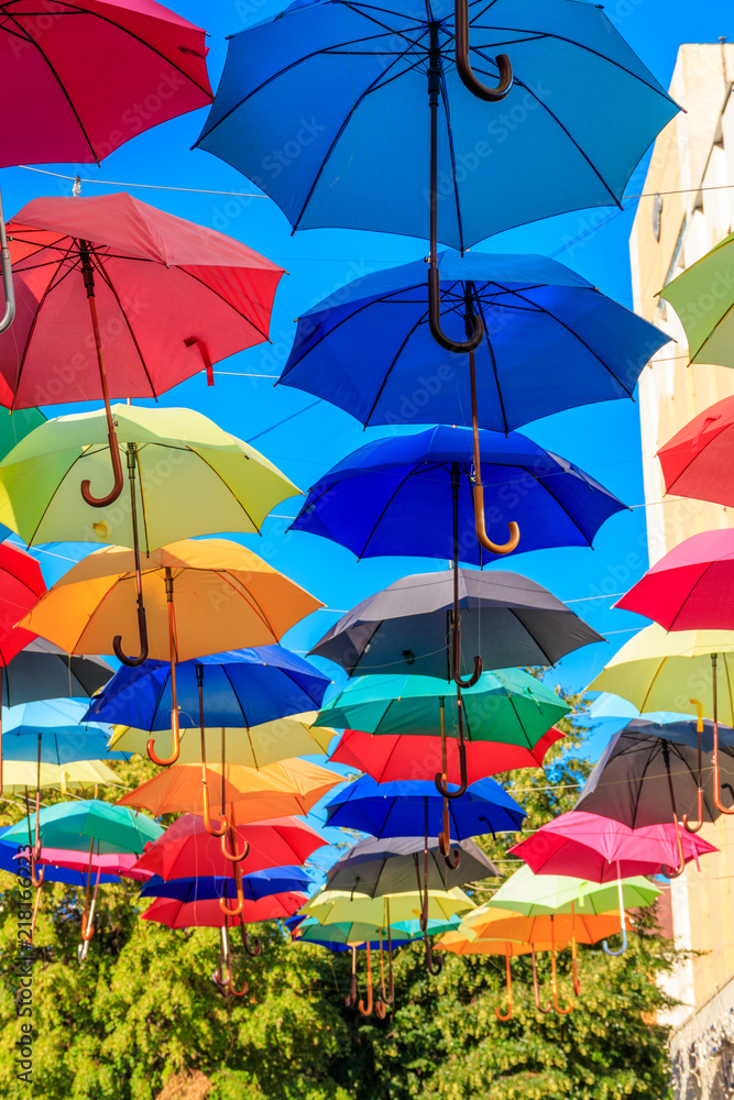Multicolored umbrellas on the city street. The city street is decorated with many colorful open umbrellas Multicolored umbrellas on the city street. The city street is decorated with many colorful open umbrellas