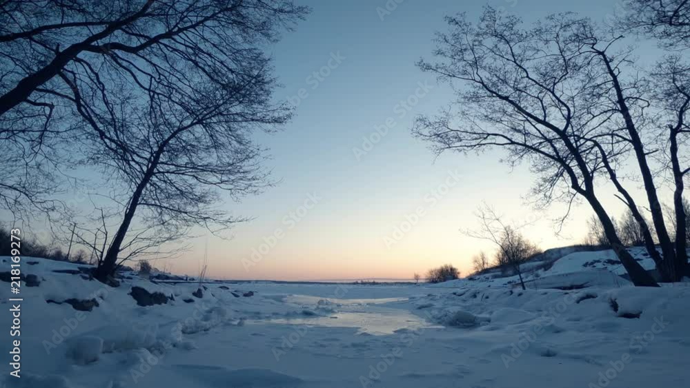 Time lapse at frozen, snowy icy sea with trees and small river during morning during sunrise. Uunisaari. Helsinki. Finland. Time lapse at frozen, snowy icy sea with trees and small river during morning during sunrise. Uunisaari. Helsinki. Finland.
